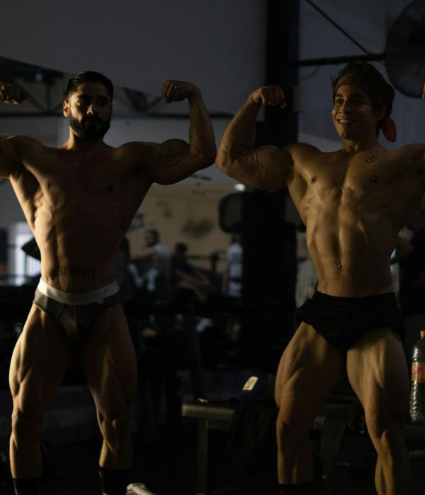 Man performing a strength exercise in a dark gym with amber light.